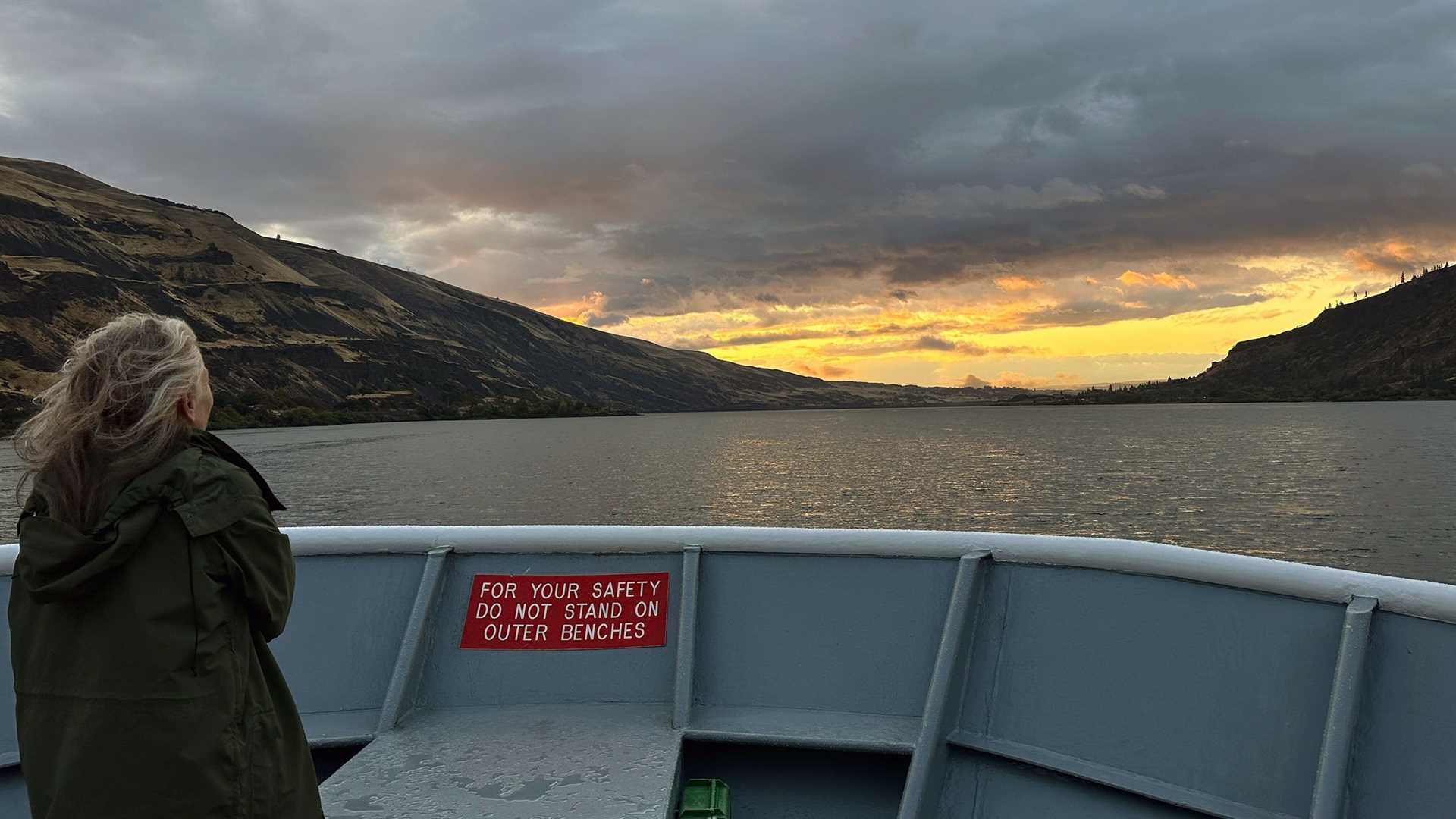 a woman standing on the bow of a ship at sunrise