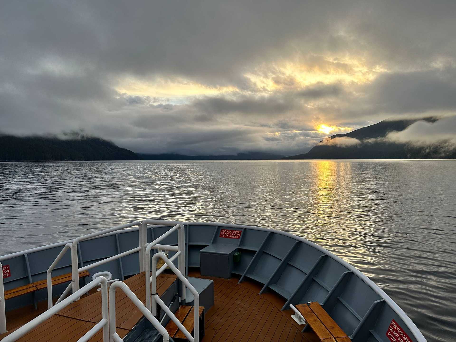 sunrise with the bow of a ship in the foreground