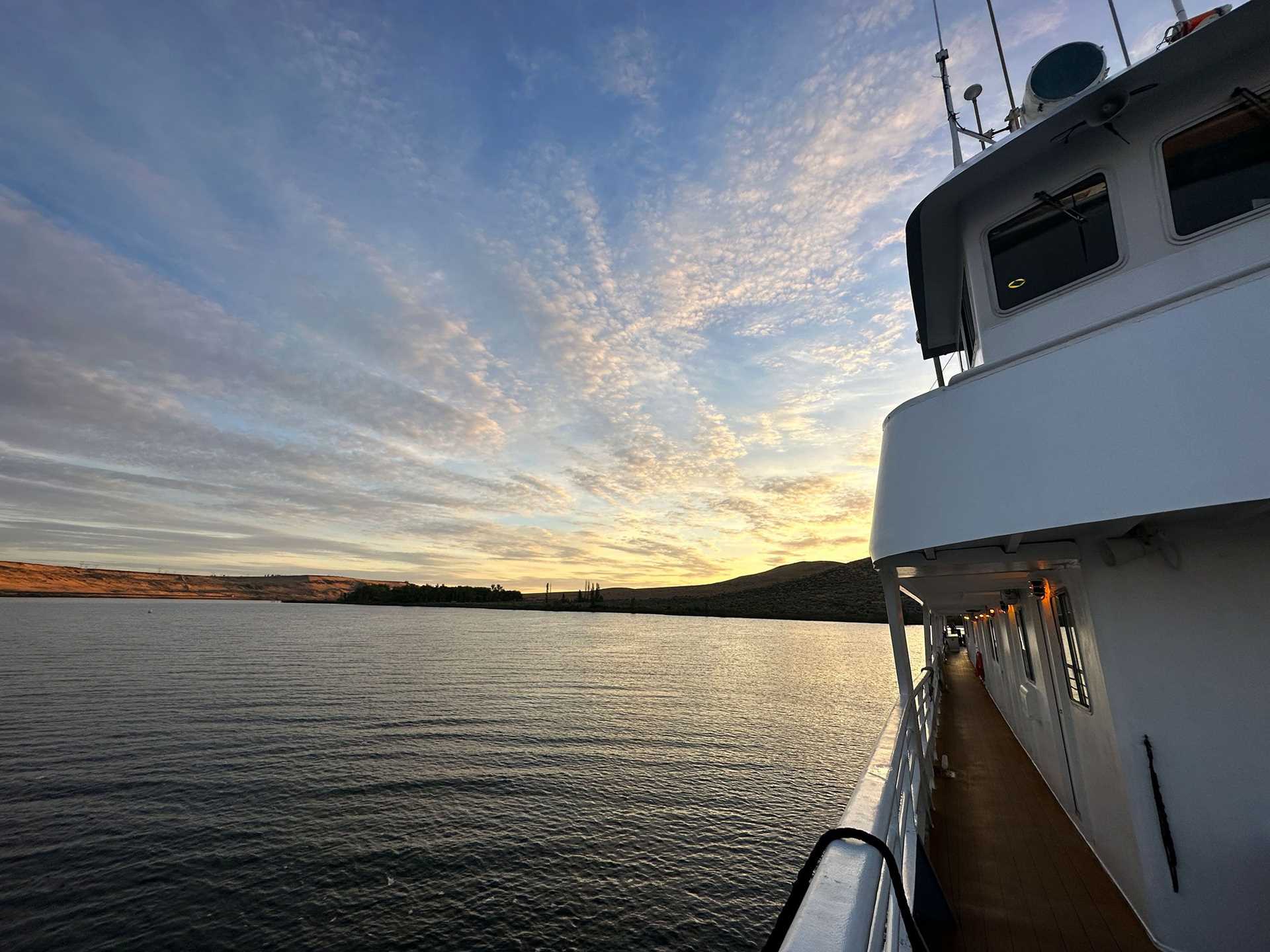 sunrise over water, with ship deck in foreground